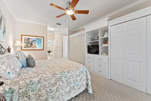 bedroom with carpet floors, crown molding, ceiling fan, and two closets