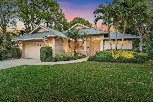 view of front of property featuring a yard, concrete driveway, metal roof, and a garage