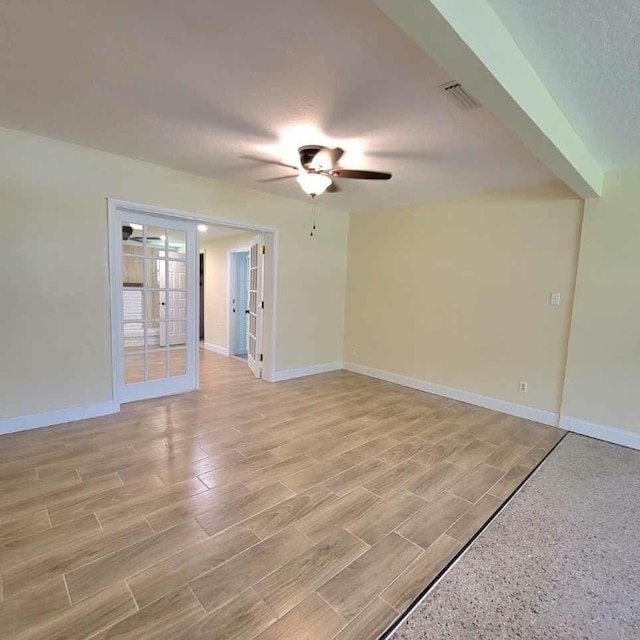 spare room with a ceiling fan, wood finish floors, visible vents, and baseboards