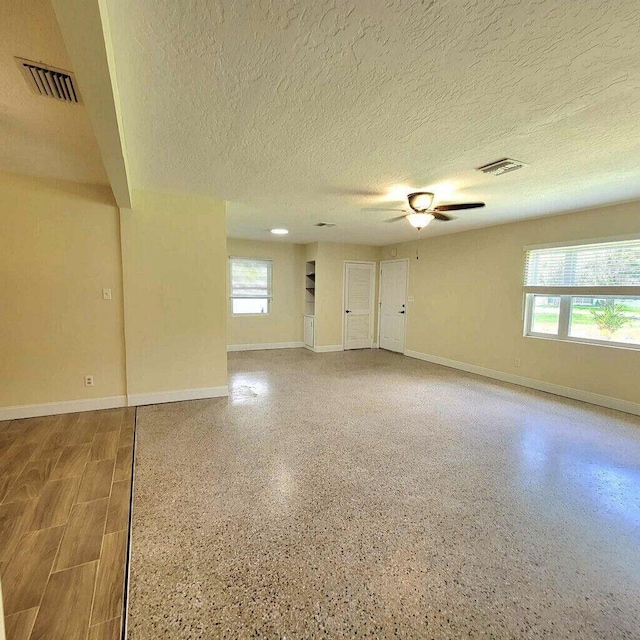 spare room with ceiling fan, speckled floor, and visible vents