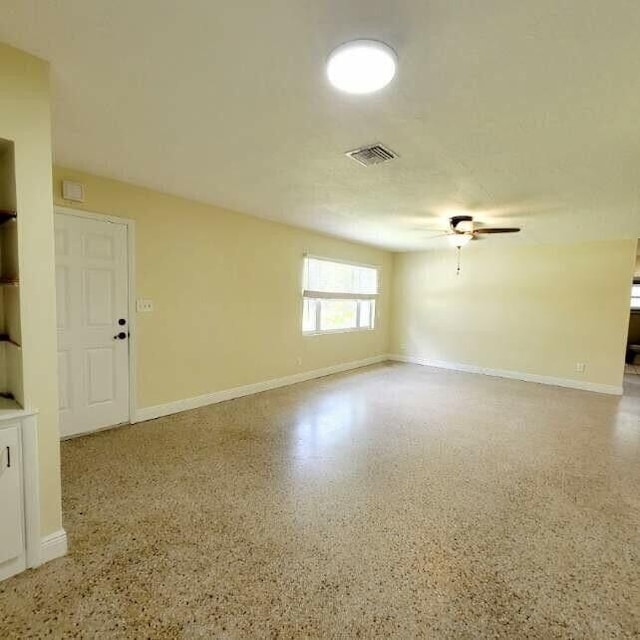 spare room with visible vents, ceiling fan, baseboards, and speckled floor