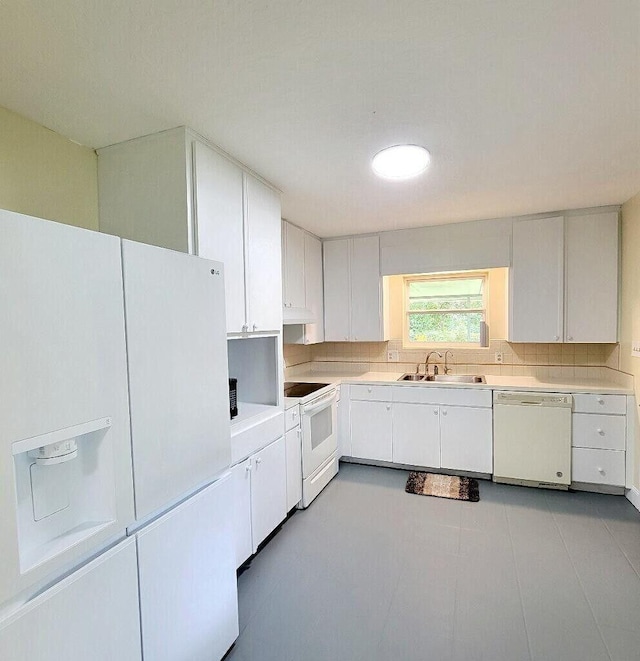 kitchen with white appliances, tasteful backsplash, light countertops, under cabinet range hood, and a sink