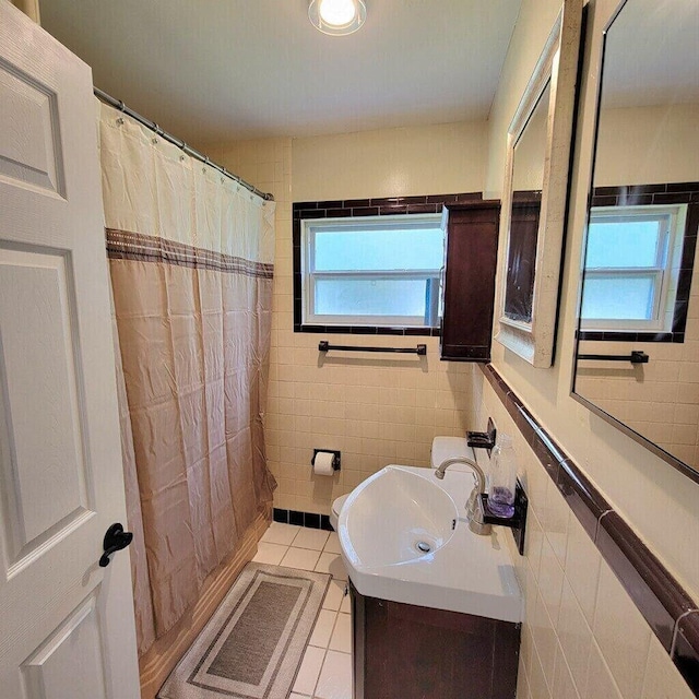 full bath with a shower with curtain, tile patterned flooring, tile walls, and vanity