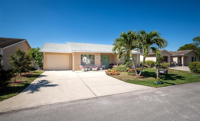 single story home with concrete driveway, stucco siding, an attached garage, and a front yard