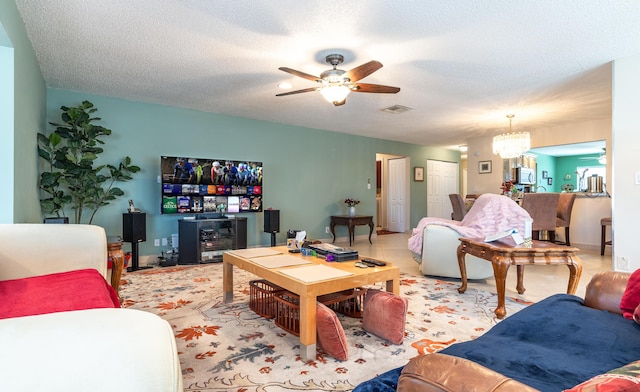 living room featuring ceiling fan with notable chandelier, a textured ceiling, and visible vents