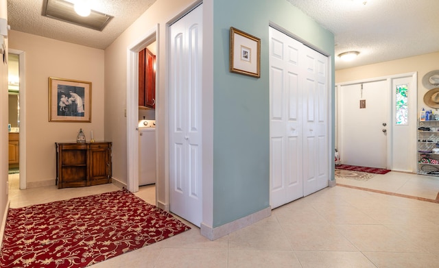 foyer featuring washer / dryer, light tile patterned flooring, and a textured ceiling