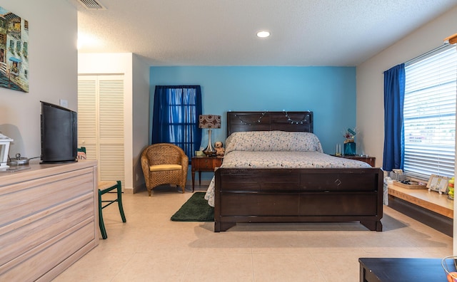 bedroom with a textured ceiling, a closet, light tile patterned flooring, and recessed lighting