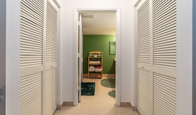 corridor featuring light tile patterned floors, visible vents, and baseboards