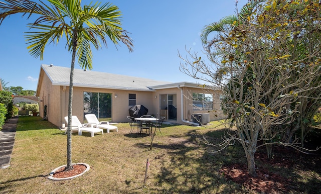 back of house featuring a lawn and stucco siding