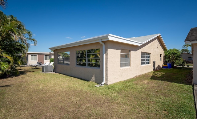 view of home's exterior featuring central AC unit, a lawn, and stucco siding