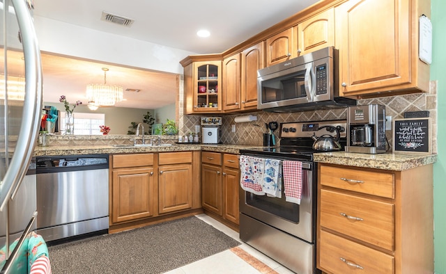 kitchen featuring stainless steel appliances, a sink, glass insert cabinets, and decorative backsplash