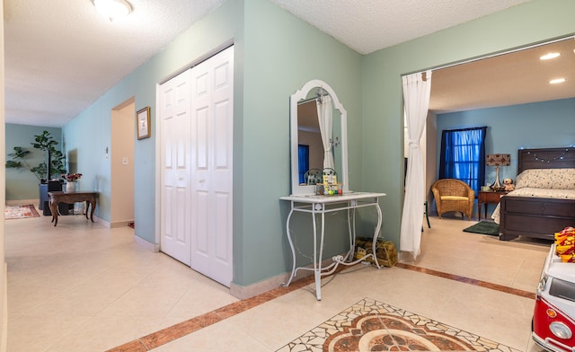 hall with tile patterned flooring, baseboards, a textured ceiling, and recessed lighting