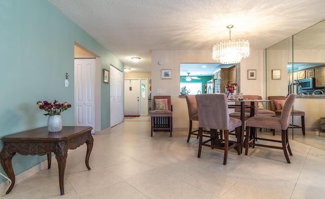 dining space with a textured ceiling, light tile patterned floors, a notable chandelier, and baseboards