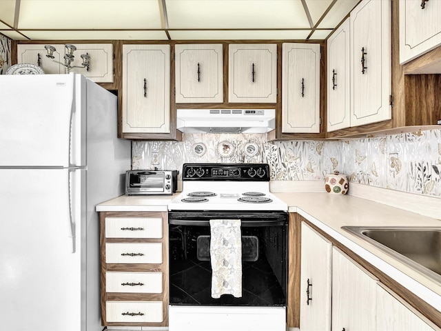 kitchen featuring electric stove, a toaster, light countertops, freestanding refrigerator, and under cabinet range hood