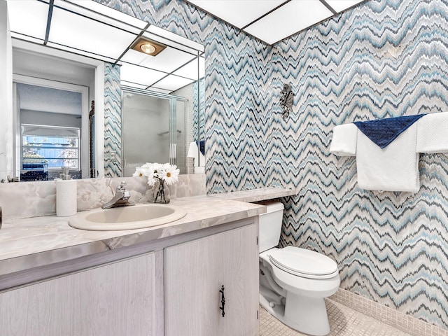 bathroom featuring wallpapered walls, toilet, a shower stall, vanity, and tile patterned floors