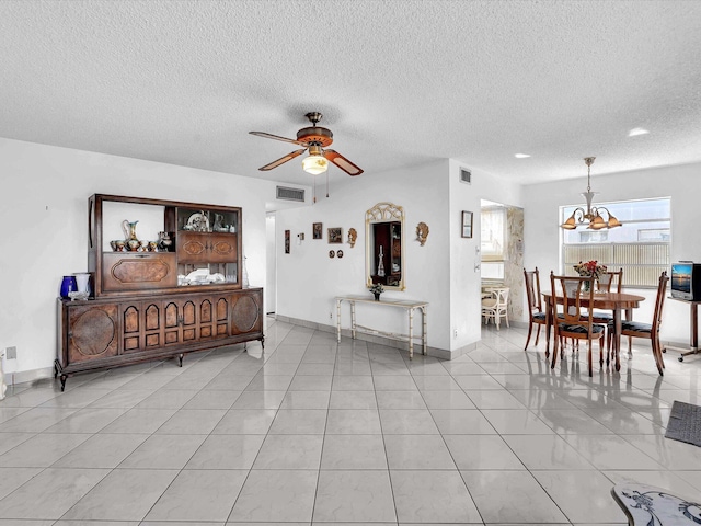 interior space with ceiling fan with notable chandelier, light tile patterned floors, and visible vents