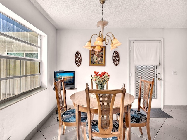 dining space with a textured ceiling, light tile patterned flooring, baseboards, and a notable chandelier