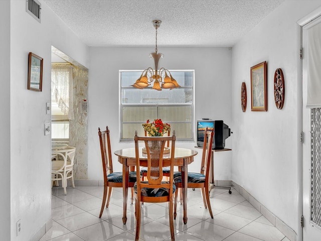 dining space featuring baseboards, visible vents, a textured ceiling, a chandelier, and light tile patterned flooring