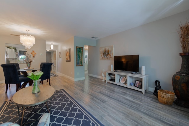 living room with a chandelier, baseboards, and wood finished floors