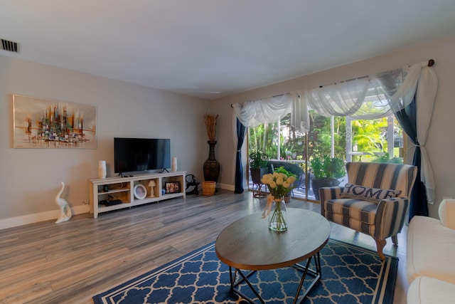 living room featuring baseboards, visible vents, and wood finished floors