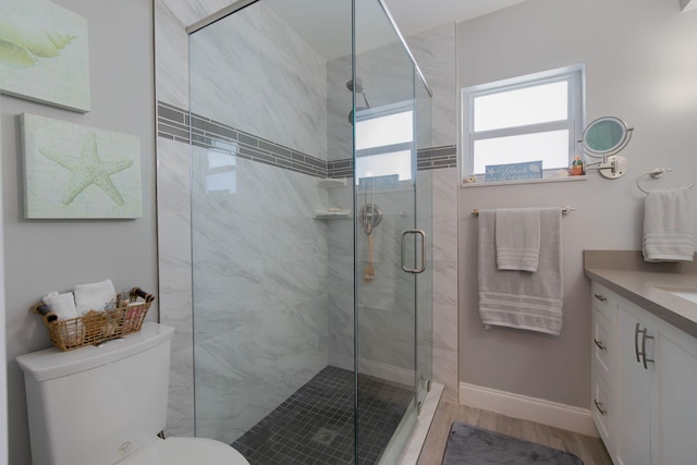 bathroom with baseboards, toilet, wood finished floors, vanity, and a shower stall