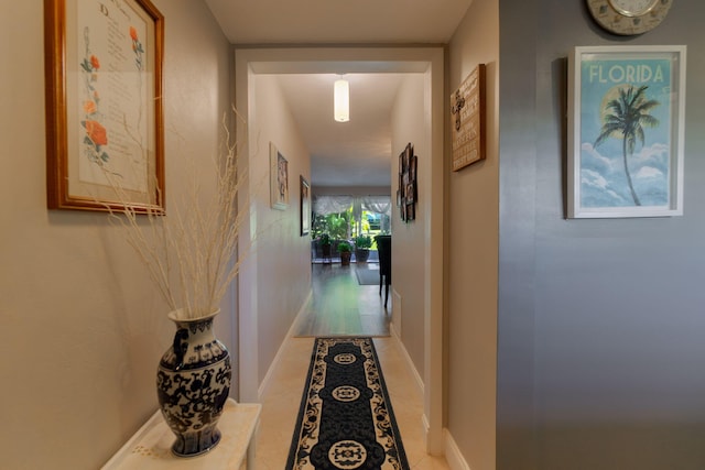 hall featuring tile patterned flooring and baseboards