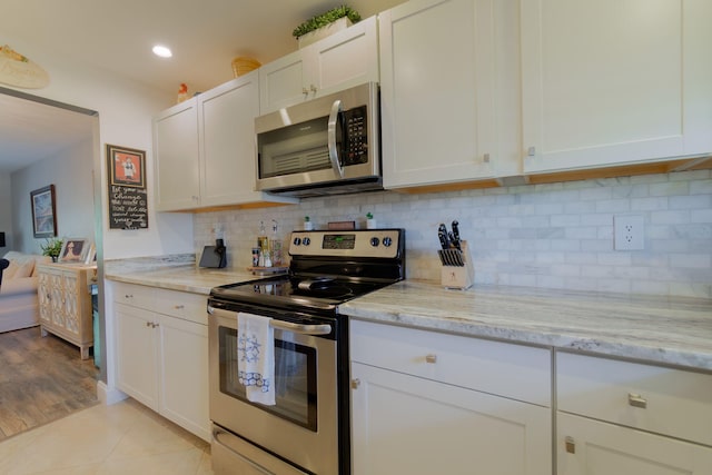 kitchen with white cabinetry, appliances with stainless steel finishes, decorative backsplash, and light stone counters