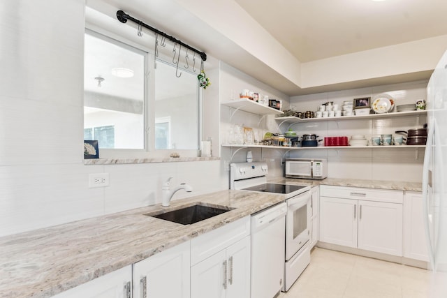 kitchen with white appliances, white cabinets, a sink, light stone countertops, and backsplash