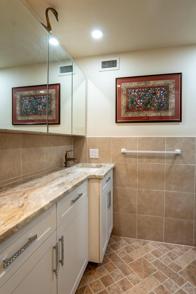 bathroom featuring recessed lighting, vanity, visible vents, and tile walls