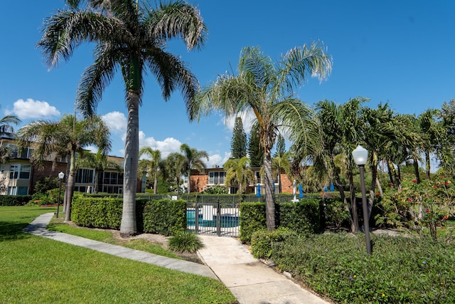 view of community with fence, a pool, and a yard