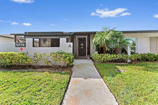 view of front of home featuring stucco siding and a front yard