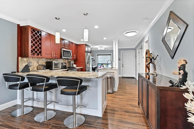 kitchen with stainless steel appliances, wood finish floors, crown molding, and a peninsula