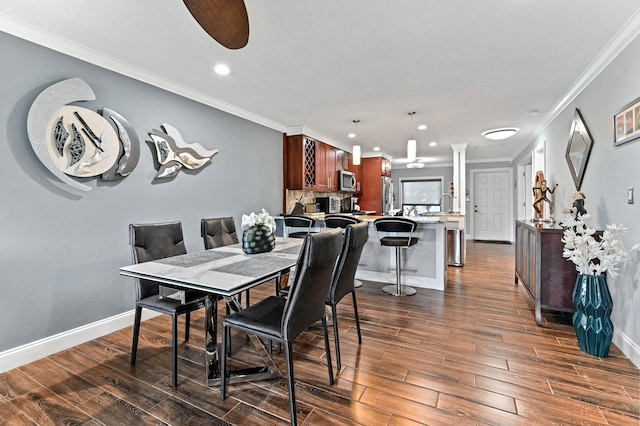 dining area with ornamental molding, dark wood finished floors, baseboards, and a ceiling fan