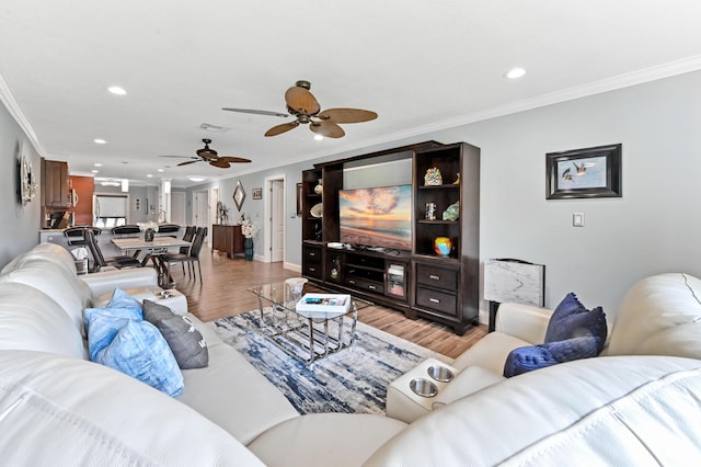 living area with visible vents, baseboards, light wood-style flooring, ornamental molding, and recessed lighting