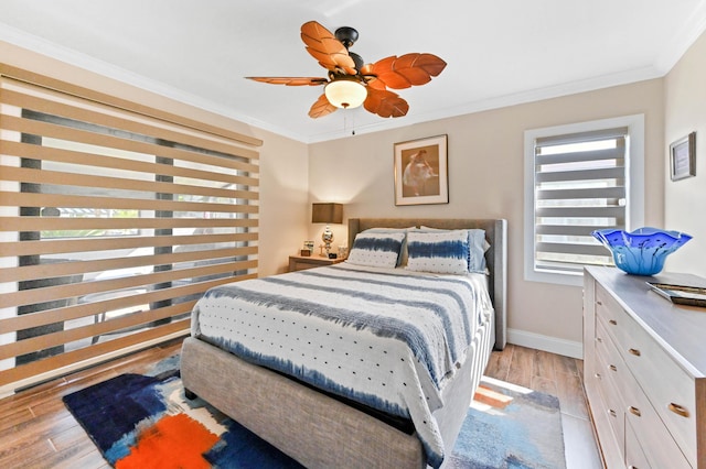 bedroom with baseboards, ceiling fan, light wood-style floors, and crown molding