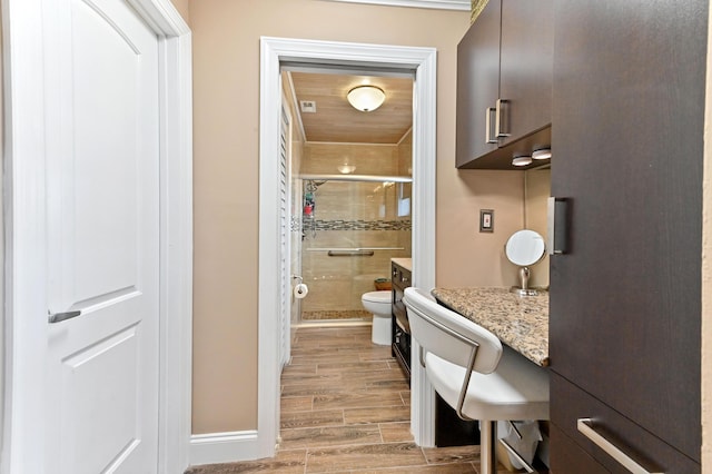 full bathroom featuring wood finish floors, a shower stall, toilet, and baseboards