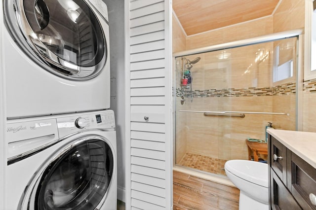 laundry room featuring laundry area, wood finish floors, and stacked washing maching and dryer