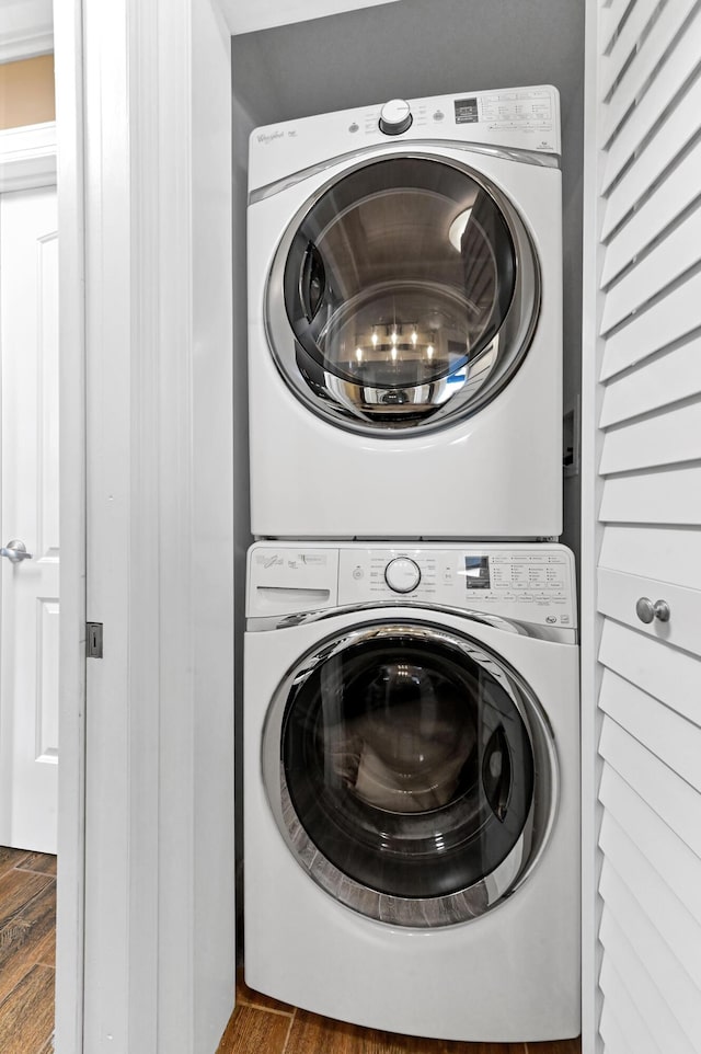 clothes washing area featuring laundry area, stacked washer / drying machine, and wood finished floors