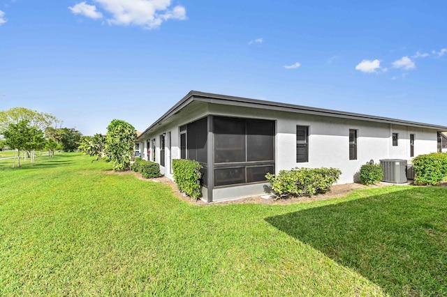 rear view of house with a yard, stucco siding, a sunroom, and central air condition unit