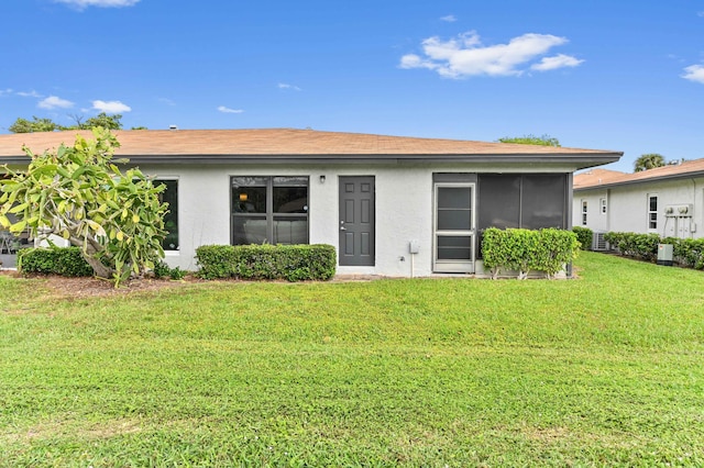 rear view of property featuring a yard and stucco siding