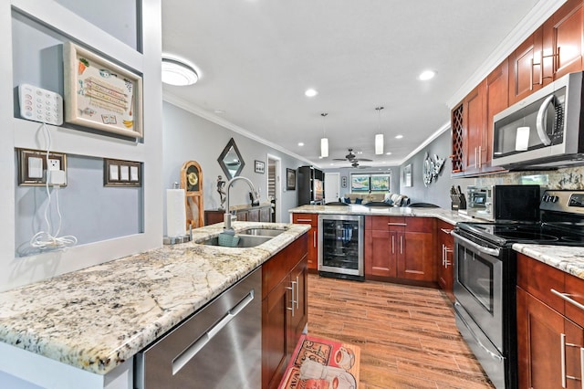 kitchen with light wood-style flooring, wine cooler, appliances with stainless steel finishes, a peninsula, and a sink