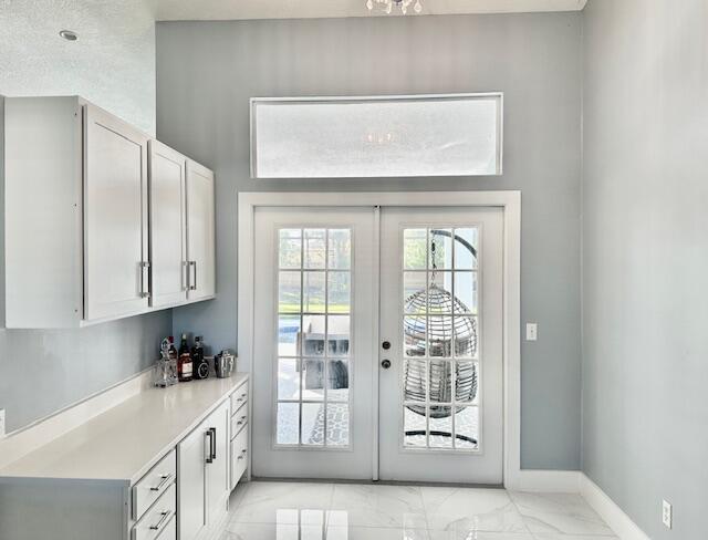 doorway with marble finish floor, baseboards, and french doors