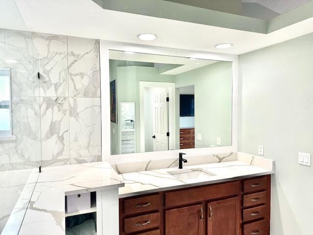 bathroom with a marble finish shower, vanity, and recessed lighting