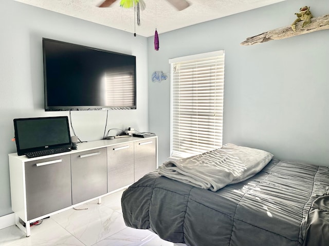 bedroom featuring marble finish floor, a ceiling fan, and a textured ceiling