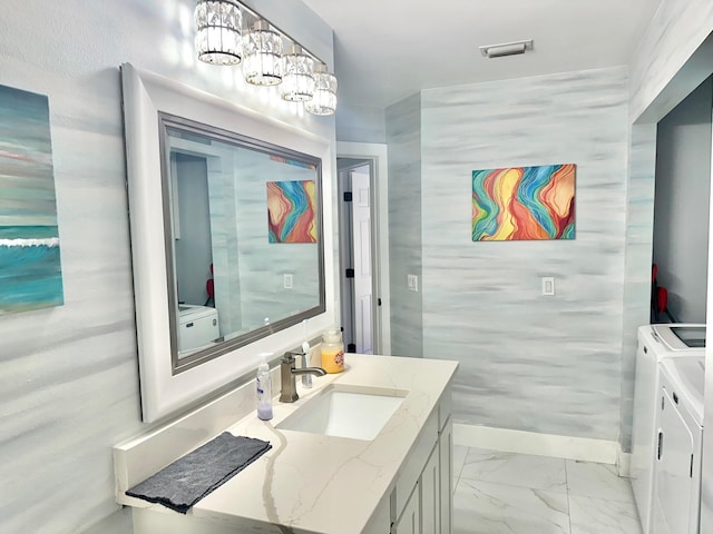 bathroom featuring marble finish floor, visible vents, washing machine and dryer, vanity, and baseboards