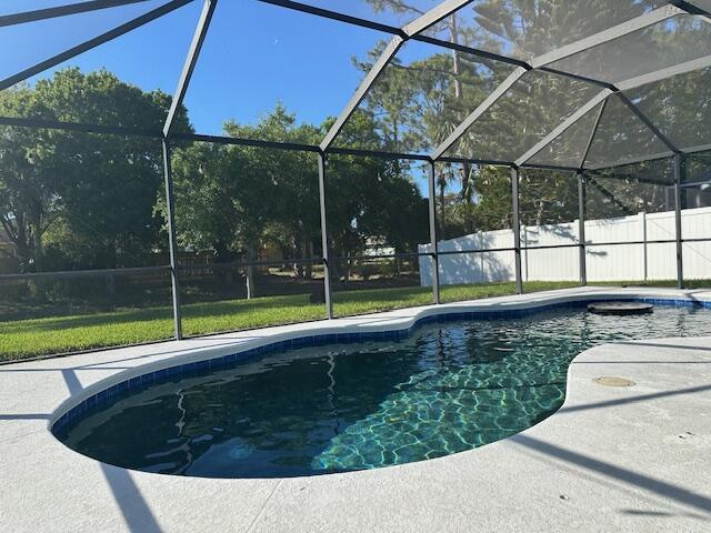 view of pool with a patio area, fence, a fenced in pool, and a lanai