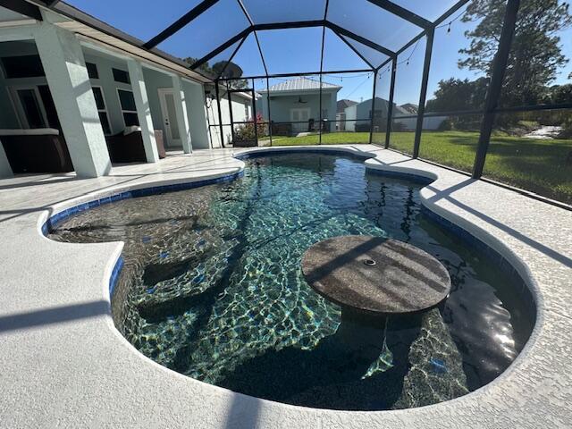 outdoor pool with glass enclosure and a patio