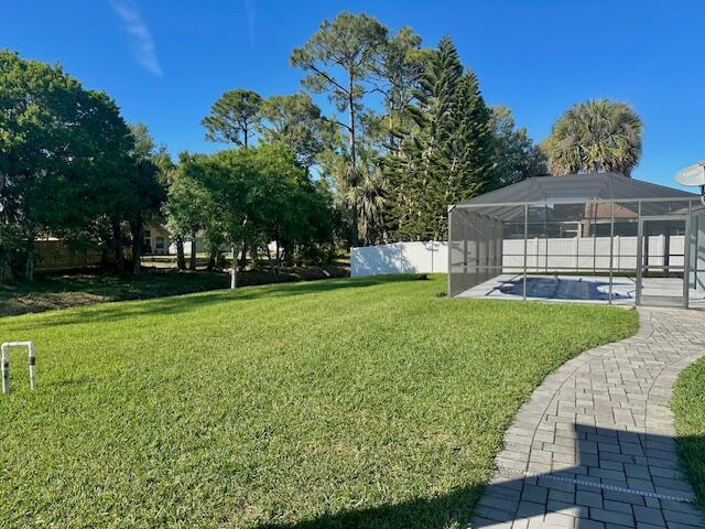 view of yard with glass enclosure, fence, and a fenced in pool