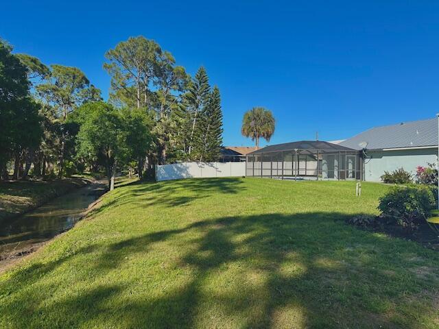 view of yard with glass enclosure and fence