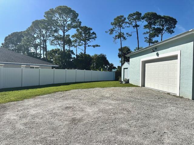 view of yard with driveway, an attached garage, and fence